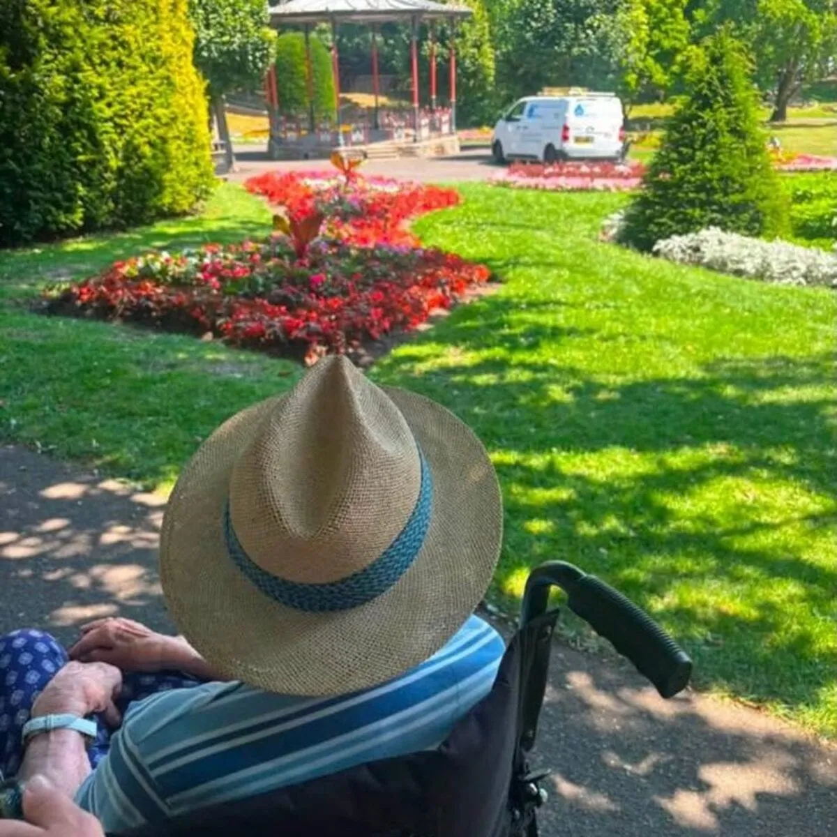 A client in a sun hat looking at flower beds in a park